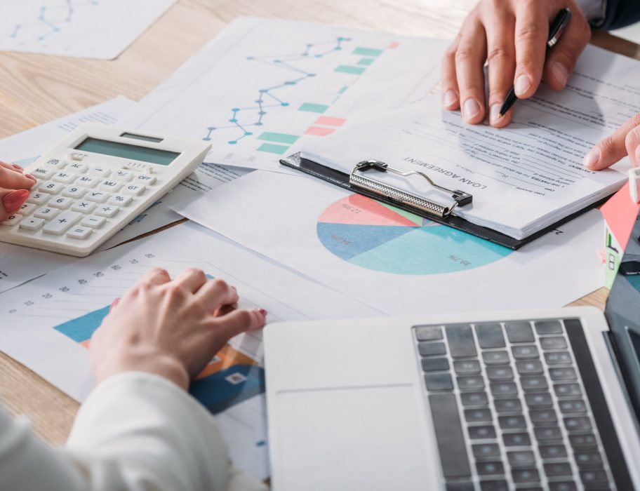 partial-view-of-man-studying-loan-agreement-and-businesswoman-using-calculator-while-sitting-at.jpg